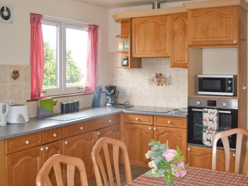 a kitchen with wooden cabinets and a table with chairs at The Junipers in Tain