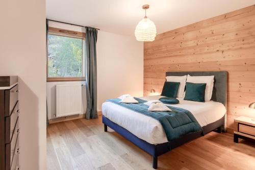 une chambre avec un grand lit avec un mur en bois dans l'établissement Appartement moderne - Les houches, aux Houches