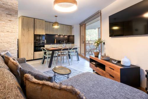 un salon avec un canapé et une cuisine avec une table dans l'établissement Appartement moderne - Les houches, aux Houches