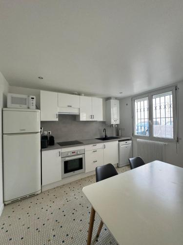 une cuisine avec des appareils blancs et une table avec des chaises dans l'établissement Charmant T2, cosy et calme, à 15 minutes de Paris, à Argenteuil