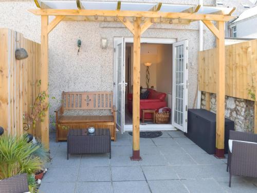 a patio with a wooden pergola and a bench at Morwood Cottage in Porthcawl