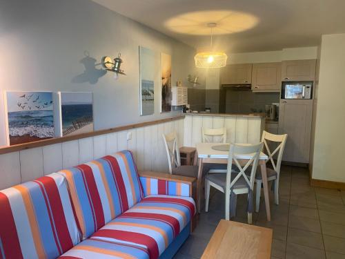 a living room with a couch and a table and a kitchen at Appartement 4 à 6 pers BELLE DUNE GARDEN - Draps Serviettes et Ménage compris in Fort-Mahon-Plage