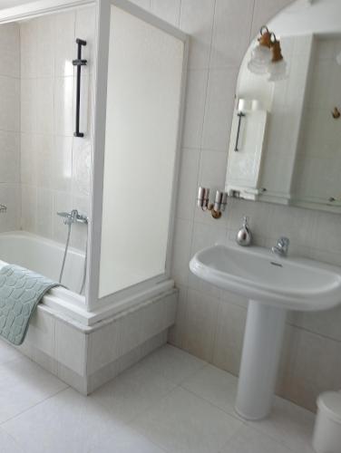 a white bathroom with a sink and a bath tub at La Chungita in Villanueva de Arosa
