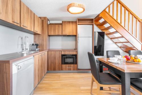 a kitchen with wooden cabinets and a table with chairs at Duplex vue dégagée, garage, local à ski, wifi, 6 pers in Isola 2000