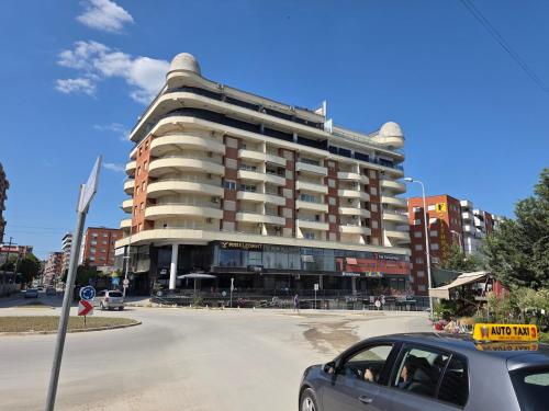 a car parked in front of a large building at Apartment 2 Plisi Gjilan in Gjilan