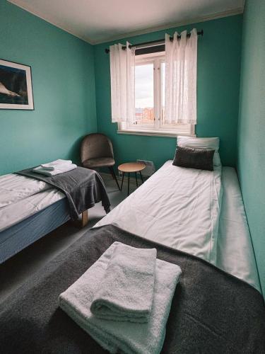 a green room with two beds and a window at Finnholmen Brygge in Henningsvær