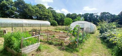 a garden with a greenhouse in a field at Chambre paisible avec jardin à la campagne en Finistère sud in Scaër
