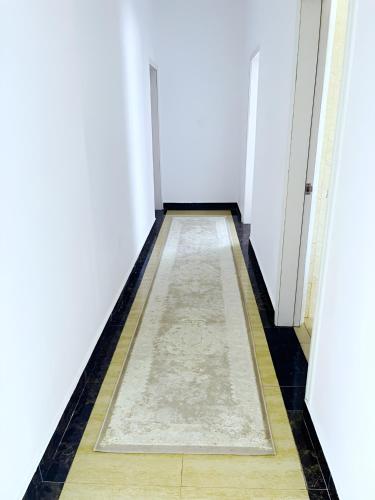 a hallway with a rug on the floor and white walls at Hembo in Lusaka