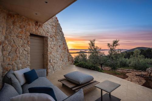 a patio with a blue couch and a stone wall at Villa Nai 3.3 in Žman