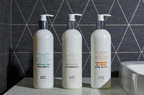 three white shampoo bottles sitting on a counter in a bathroom at Kimpton Marlowe by IHG in Cambridge