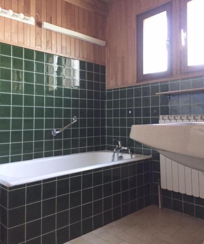 La salle de bains est pourvue de carrelage vert, d'une baignoire et d'un lavabo. dans l'établissement All-wood chalet in Haute-Savoie, à Nancy-sur-Cluses