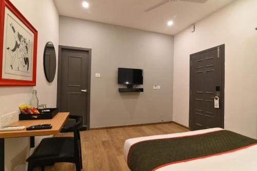 a bedroom with a bed and a desk and a tv at Super Townhouse Royapettah Near U.S Consulate in Chennai