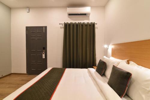 a bedroom with a large bed and a black door at Super Townhouse Royapettah Near U.S Consulate in Chennai