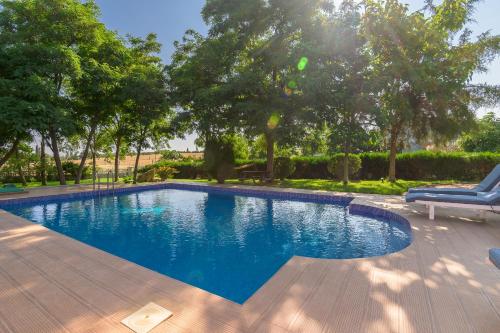 a blue swimming pool with a chair and trees at Villa Romy in Alexandroupoli