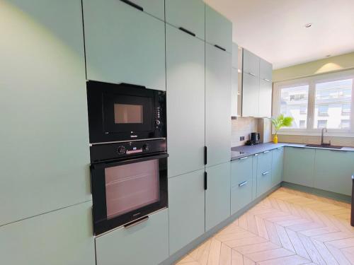 une cuisine avec des placards blancs, un four micro-ondes et une télévision dans l'établissement Paris Queen Suite with air-condition and parking, à Bourg-la-Reine