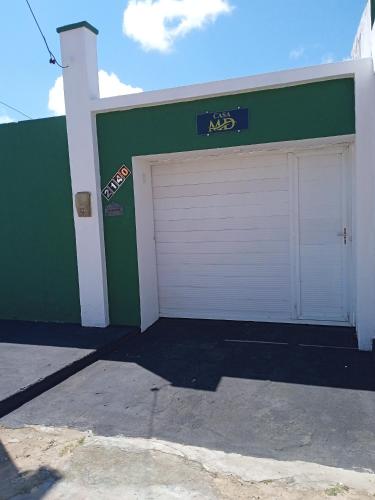 a green building with two garage doors on it at Casa MD in Camocim