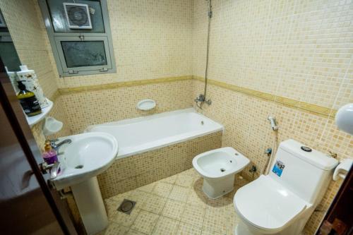 a bathroom with a toilet and a tub and a sink at PRIVATE FAMILY ROOM BY BJ in Abu Dhabi