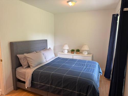 a bedroom with a bed with a blue comforter at Le Chalet Blanc, bord de lac & spa in Saint Adolphe D'Howard