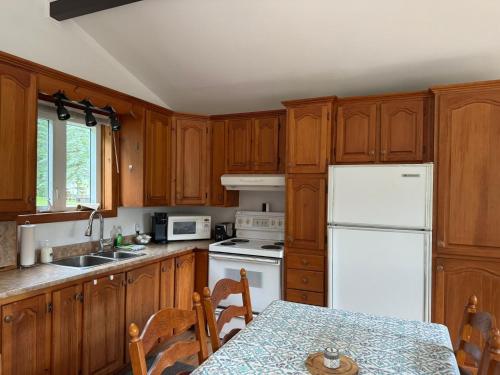 a kitchen with wooden cabinets and a white refrigerator at Le Chalet Blanc, bord de lac & spa in Saint Adolphe D'Howard