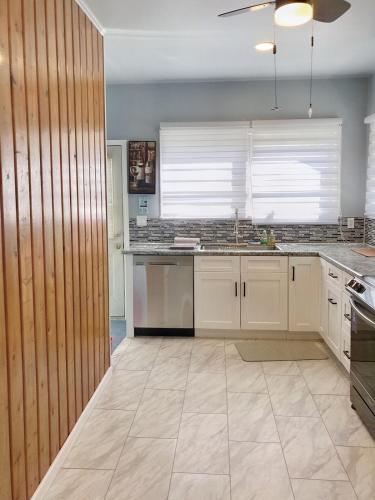 a kitchen with white cabinets and a tile floor at 2 BR Quaint Private Bungalow NR Downtown & Beaches in Pensacola