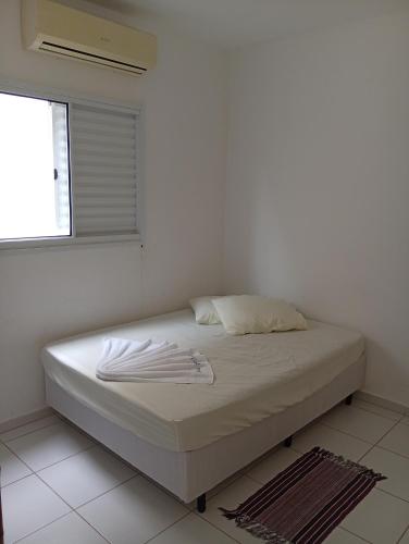 a white bed in a room with a window at Casa de férias Pôr do Sol in Presidente Epitácio