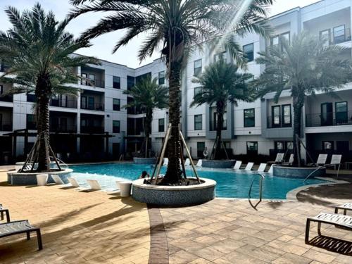 a swimming pool with palm trees in front of a building at New! 1 Bed 1 Bath Medical Center NRG Area Middle of Everywhere in Houston
