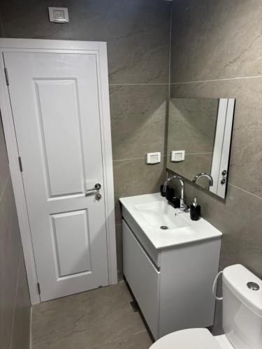 Un baño con inodoro, lavabo y espejo. en UpTown Suites, en Bat Yam