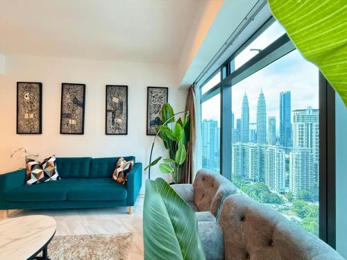 a living room with a blue couch and a large window at Eaton Residences KLCC in Kuala Lumpur