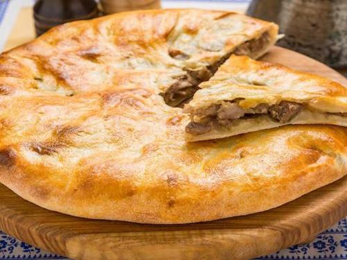 a pizza sitting on top of a wooden cutting board at Hillside Mestia ჰილსაიდ მესტია in Mestia
