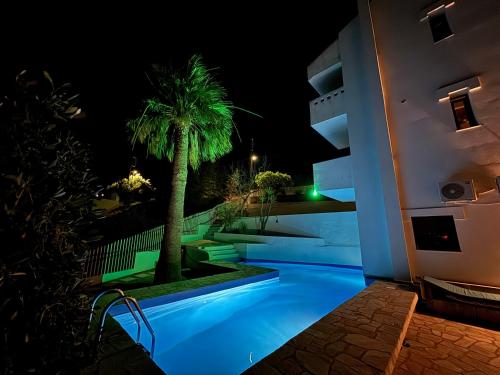 a night view of a building with a palm tree at 2 bedroom self-contained apartment and swimming pool at Palm Tree Villa in Anavissos