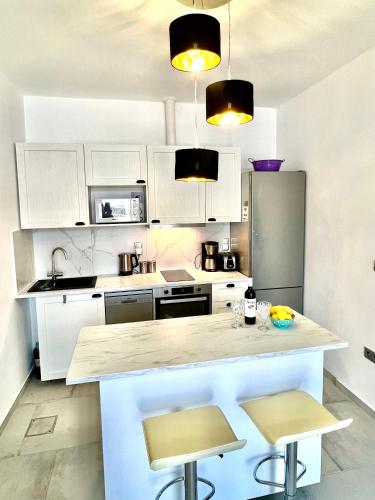 a kitchen with white cabinets and a counter with stools at 2 bedroom self-contained apartment and swimming pool at Palm Tree Villa in Anavissos