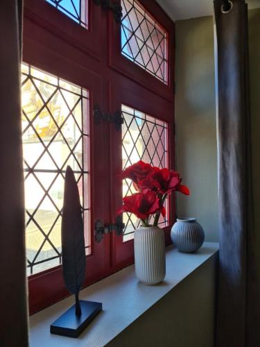 une fenêtre avec deux vases sur une étagère avec des fleurs dans l'établissement LE GOUET - Maison de la Barrière, à Saint-Brieuc
