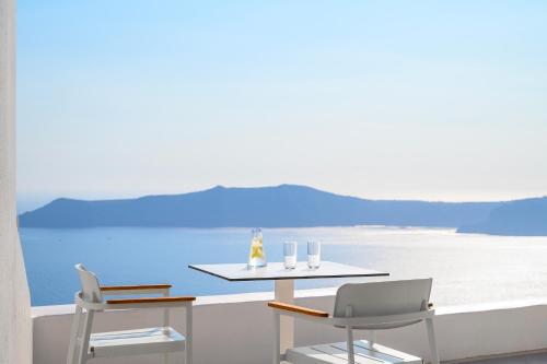 a table and chairs on a balcony with the ocean at Astra Suites in Imerovigli