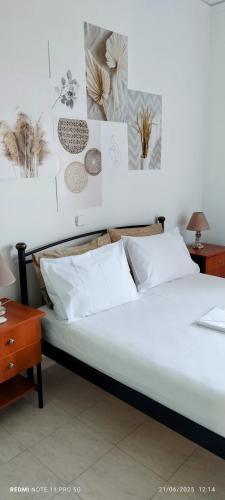 a bed with white pillows and pictures on the wall at ΑLEXANDRAS HOUSE in Preveza