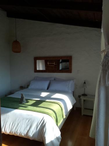 a bedroom with a white bed with a green blanket at San Mateo Hotel Campestre in Nobsa