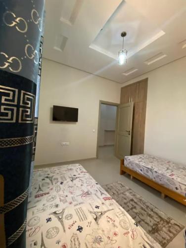 a bedroom with two beds and a tv on the wall at Downtown apartment in Agadir