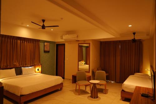 a hotel room with two beds and a table and chairs at Hotel river view sringeri in Sringeri