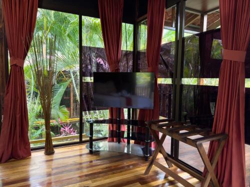 a living room with a tv and a large window at Hotel Heliconias Nature Inn & Hot Springs in Fortuna