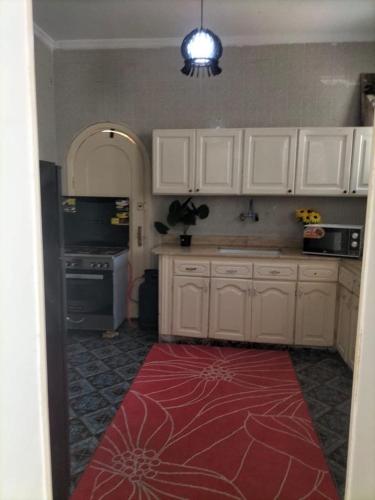 a kitchen with white cabinets and a red rug at Stand alone Villa Seabreeze with private pool in Alexandria