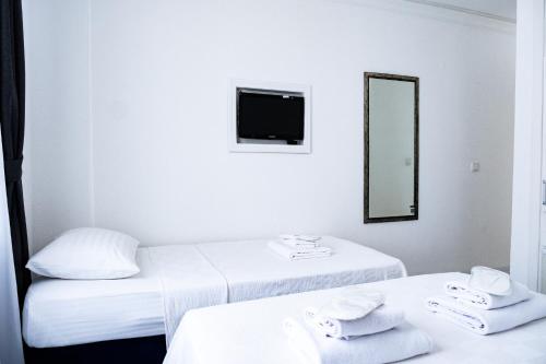 a white room with two beds and a mirror at Mauna Hotel in Bozcaada