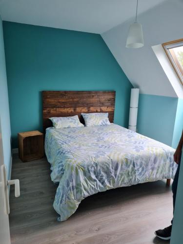 une chambre avec un lit avec un mur bleu dans l'établissement Les Pélicans, au Tréport