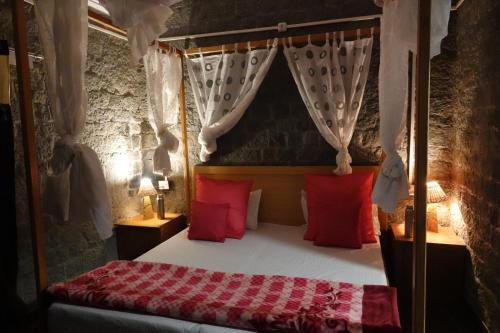 卡绍利Heritage homestays的一间卧室配有一张带红色枕头的天蓬床