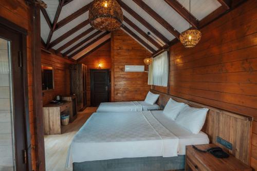 a bedroom with two beds in a wooden room at Sea Valley Lodge in Faralya