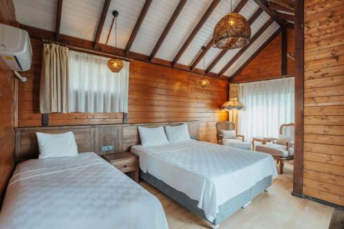 two beds in a room with wooden walls at Sea Valley Lodge in Faralya