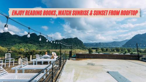 a table and chairs on a patio with mountains in the background at Green Riverside Cosy Home in Bố Trạch