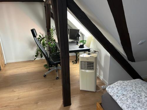 a attic room with a desk with a computer and a chair at Schöne neue DG Wohnung mit sonniger Dachterrasse und fantastischem Ausblick in Naumburg