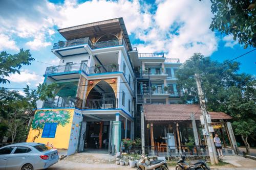 a blue and yellow building with a car parked in front at Green Riverside Cosy Home in Bố Trạch