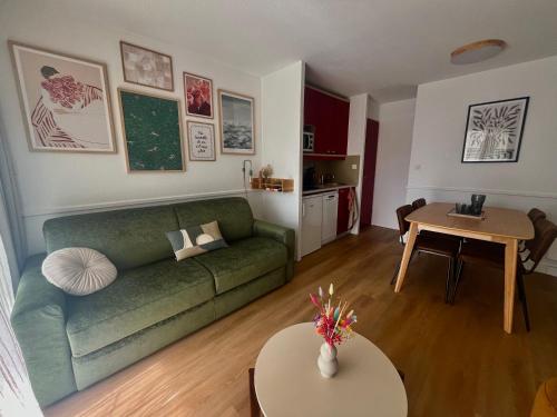 un salon avec un canapé vert et une table dans l'établissement Cocoon Albatros, Golf view, pool, pine trees and ocean, à Moliets-et-Maa