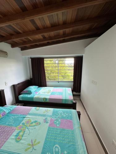 two beds in a room with a window at Casa en Marinilla cerca a guatape y el peñol in Marinilla