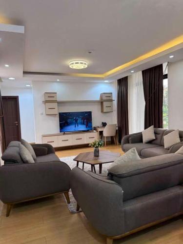 a living room with two couches and a flat screen tv at Cascadia Hotel Apartments by GF Greenland in Kigali